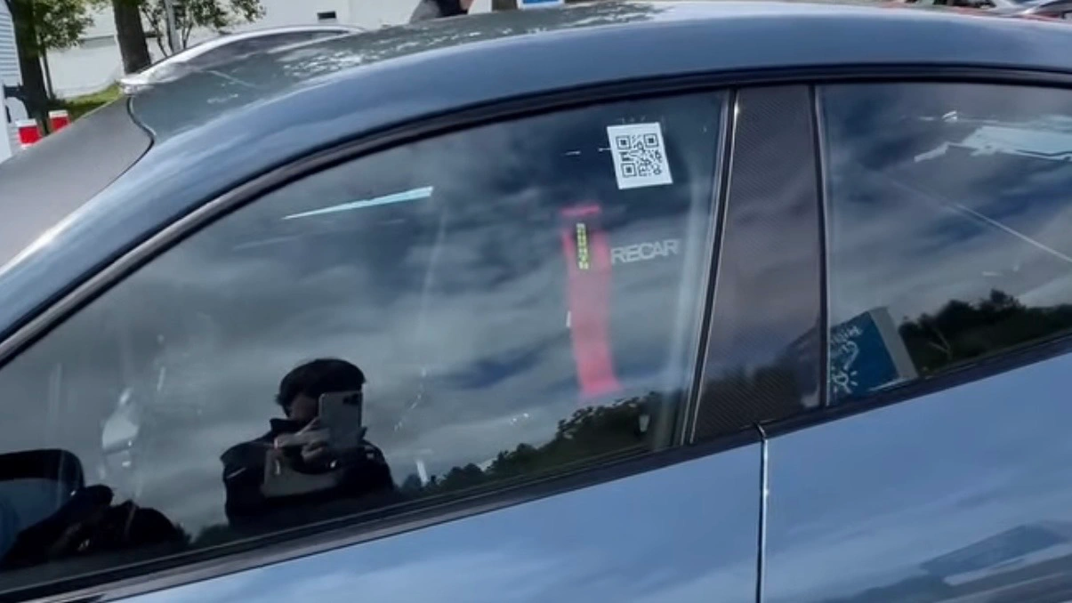 Blick durch die Seitenscheibe des rekordverdächtigen Taycan auf die rot-gelben Rennsicherheitsgurte und den Aufkleber mit der Aufschrift „RECARO“