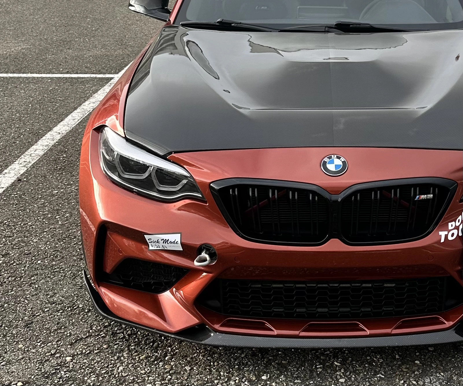 Ein orangefarbener BMW M2 mit Anhängerkupplung