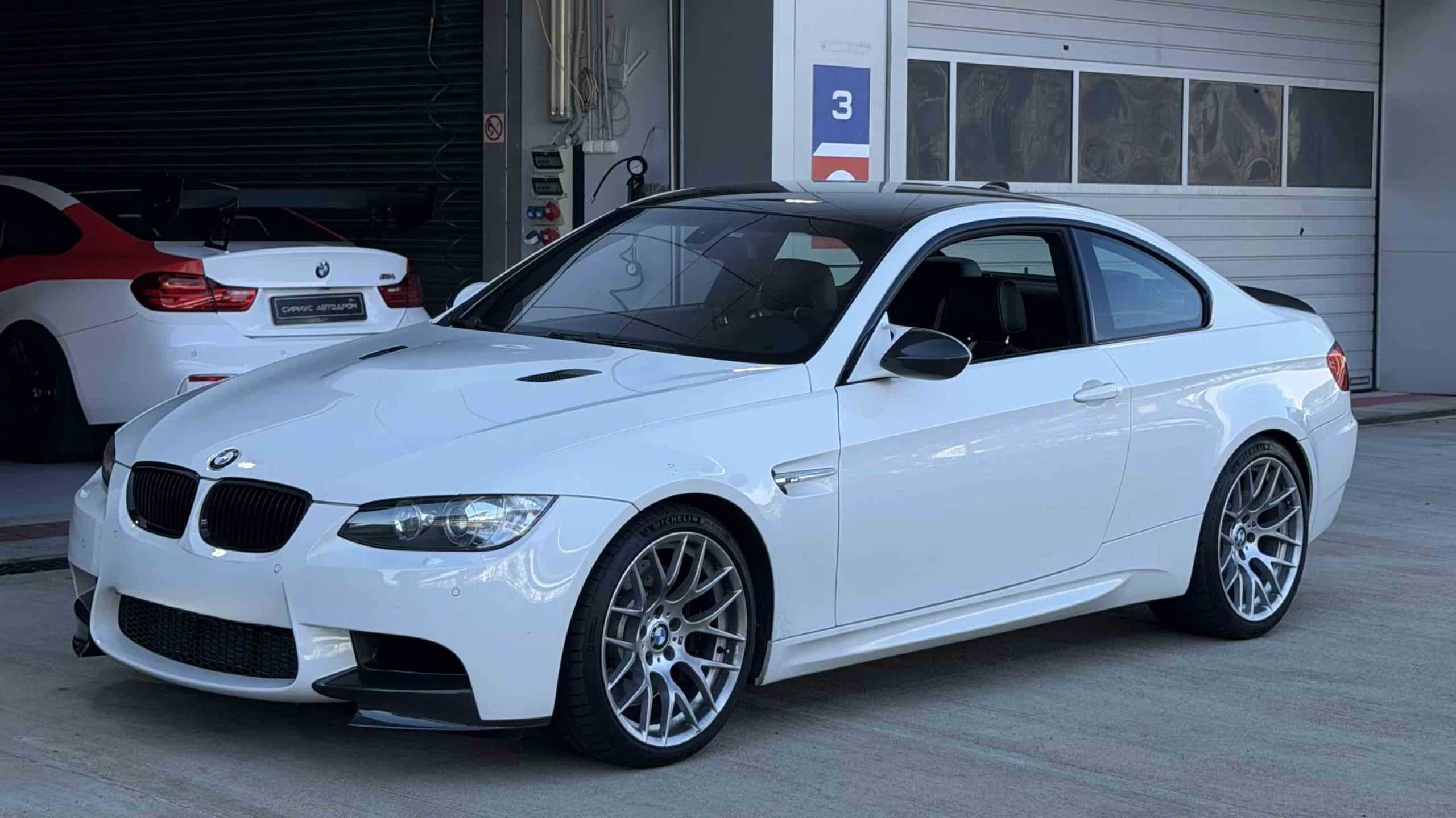 Ein weißer BMW M3 E92 mit Originalfelgen vom Typ Style 359M vor der Einfahrt auf die Rennstrecke über die Boxengasse