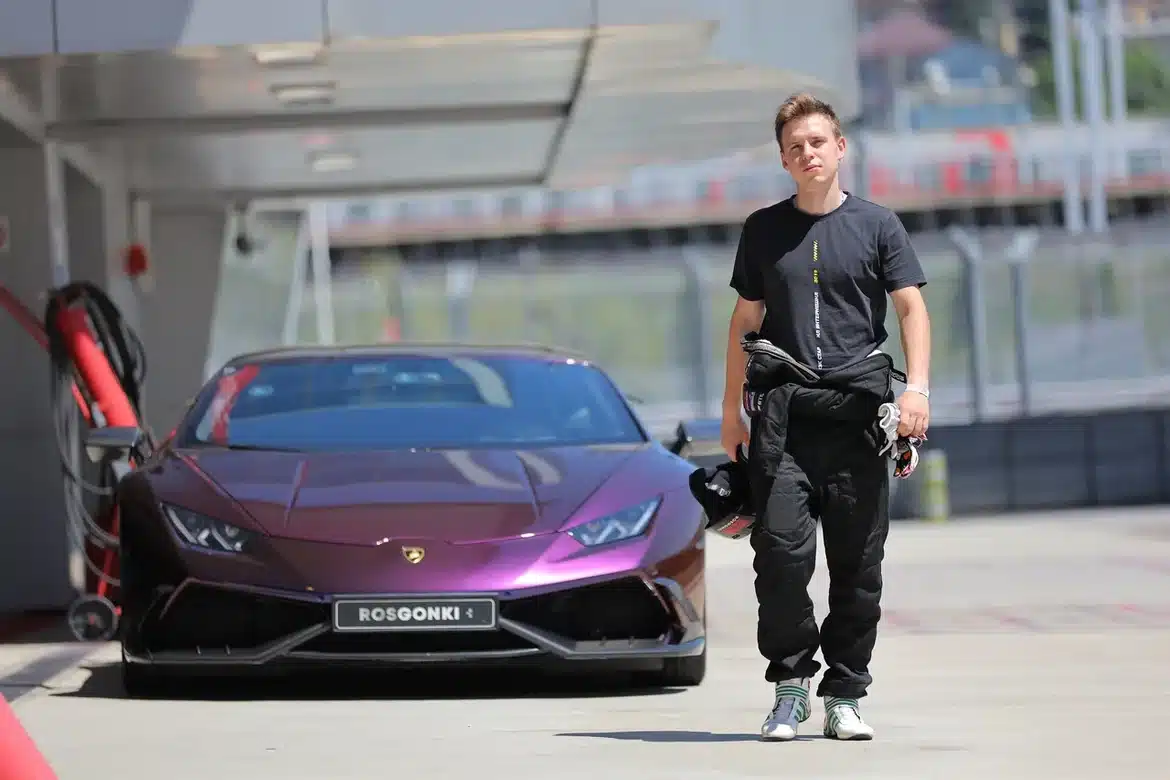 Ich bin Motorsport-Ausbilder am Sochi Autodrom; neben mir steht ein Lamborghini Huracán in der Boxengasse vor den Rennen.