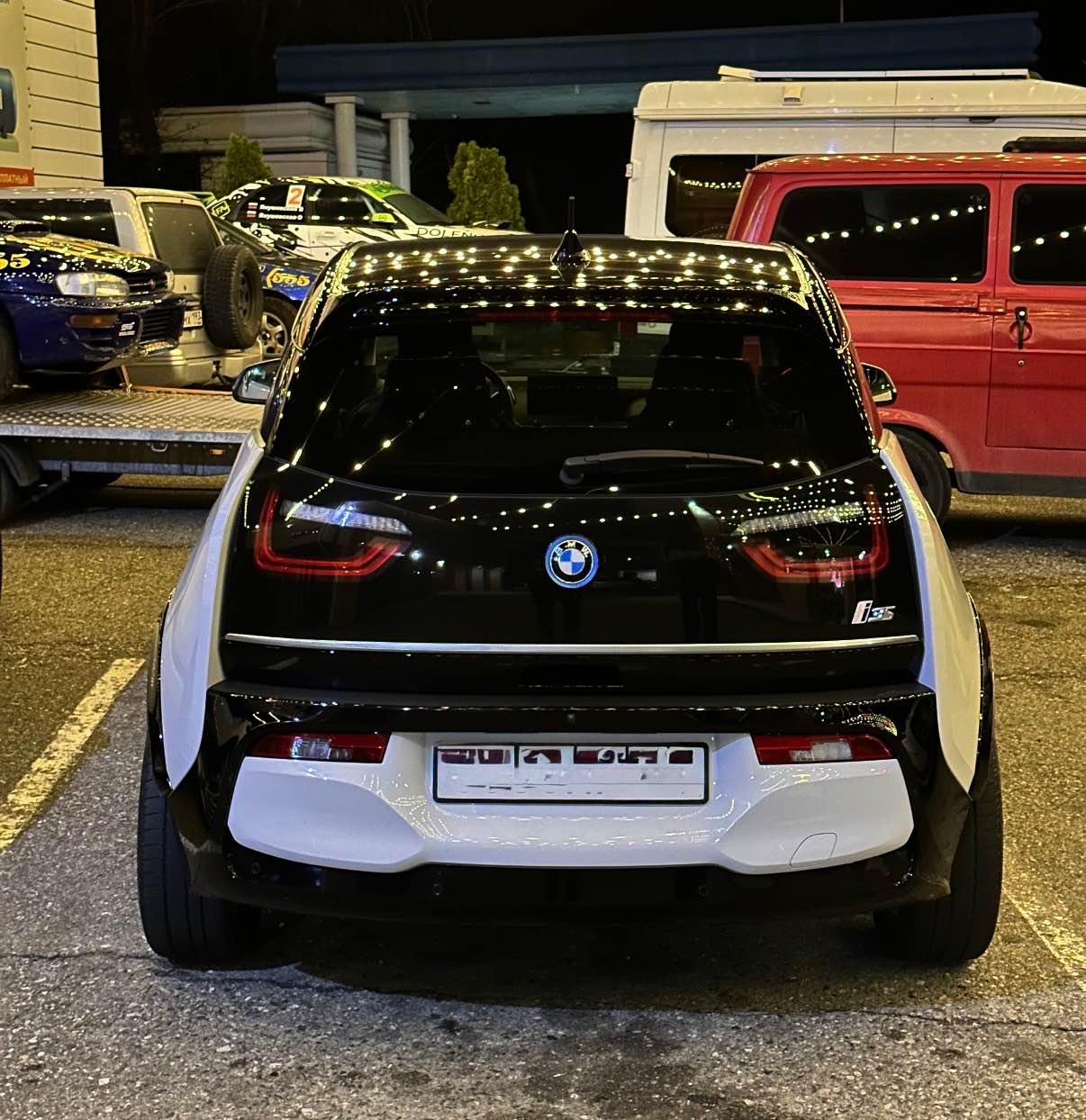 Das Heck des BMW i3s mit eingeschalteten LED-Rückleuchten bei Nacht im Parklicht.