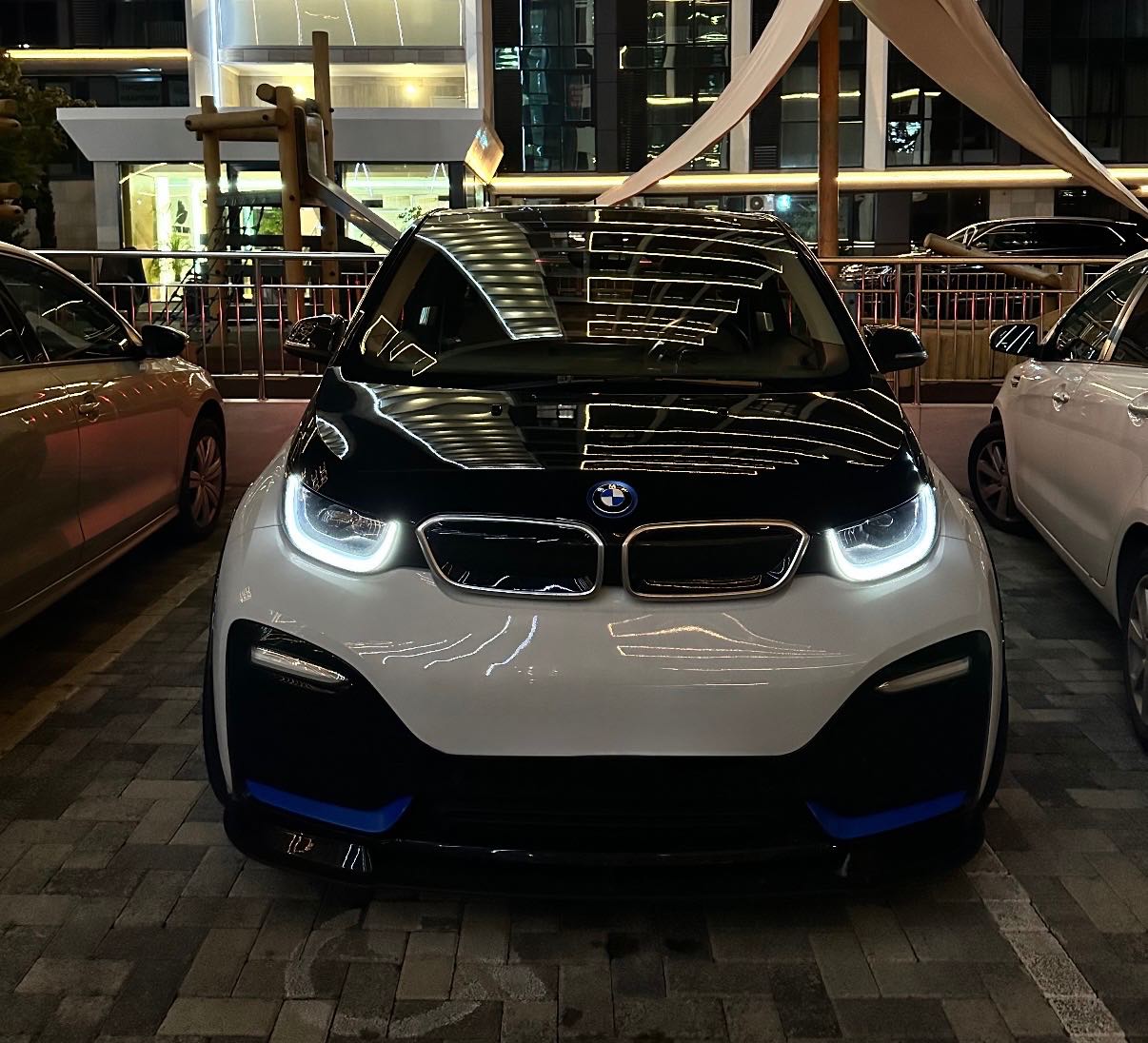 Ein BMW i3s bei Nacht mit eingeschalteten LED-Scheinwerfern.