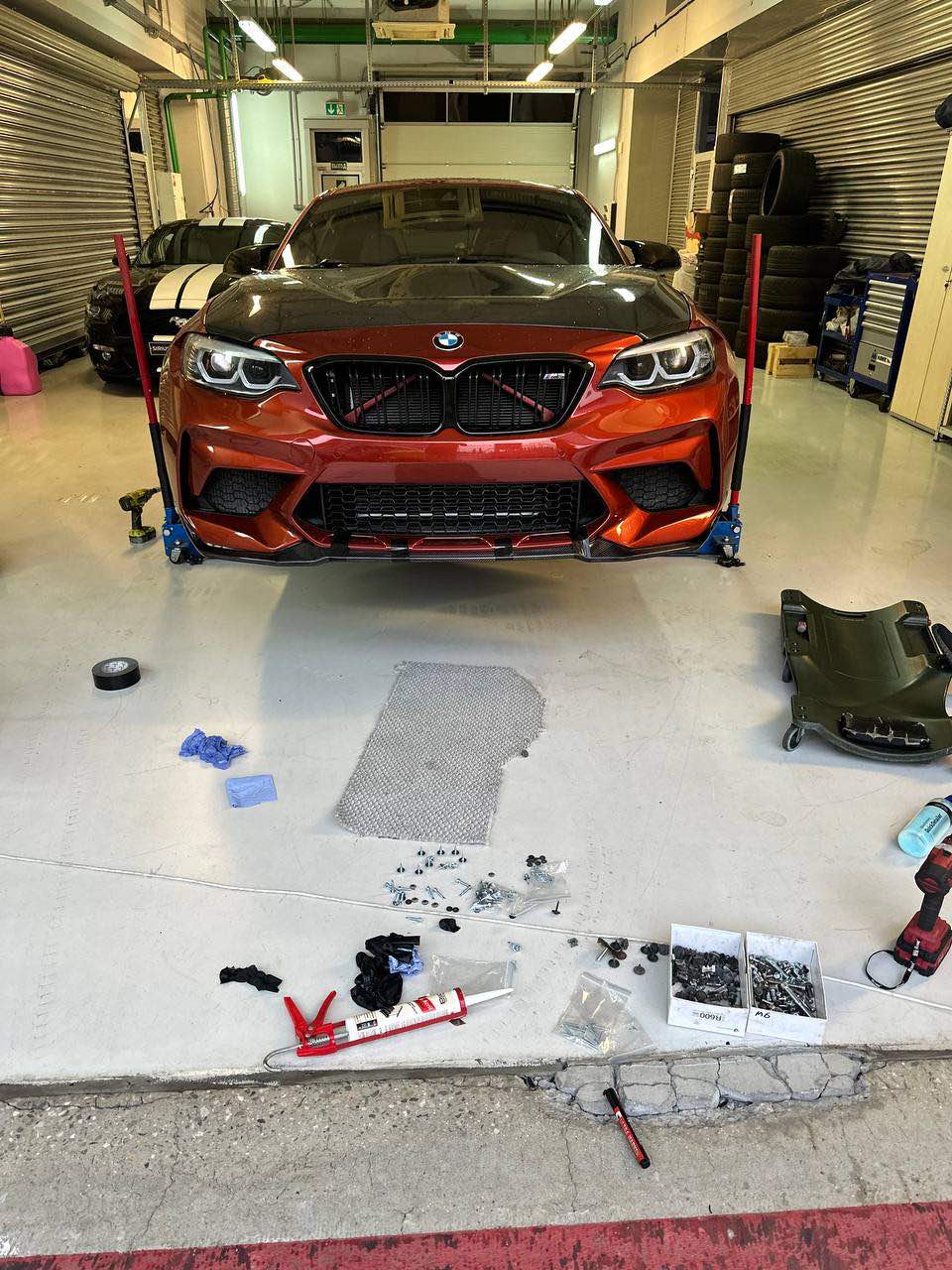 Ein BMW M2 Competition steht während der Wartung auf Wagenhebern in der Werkstatt