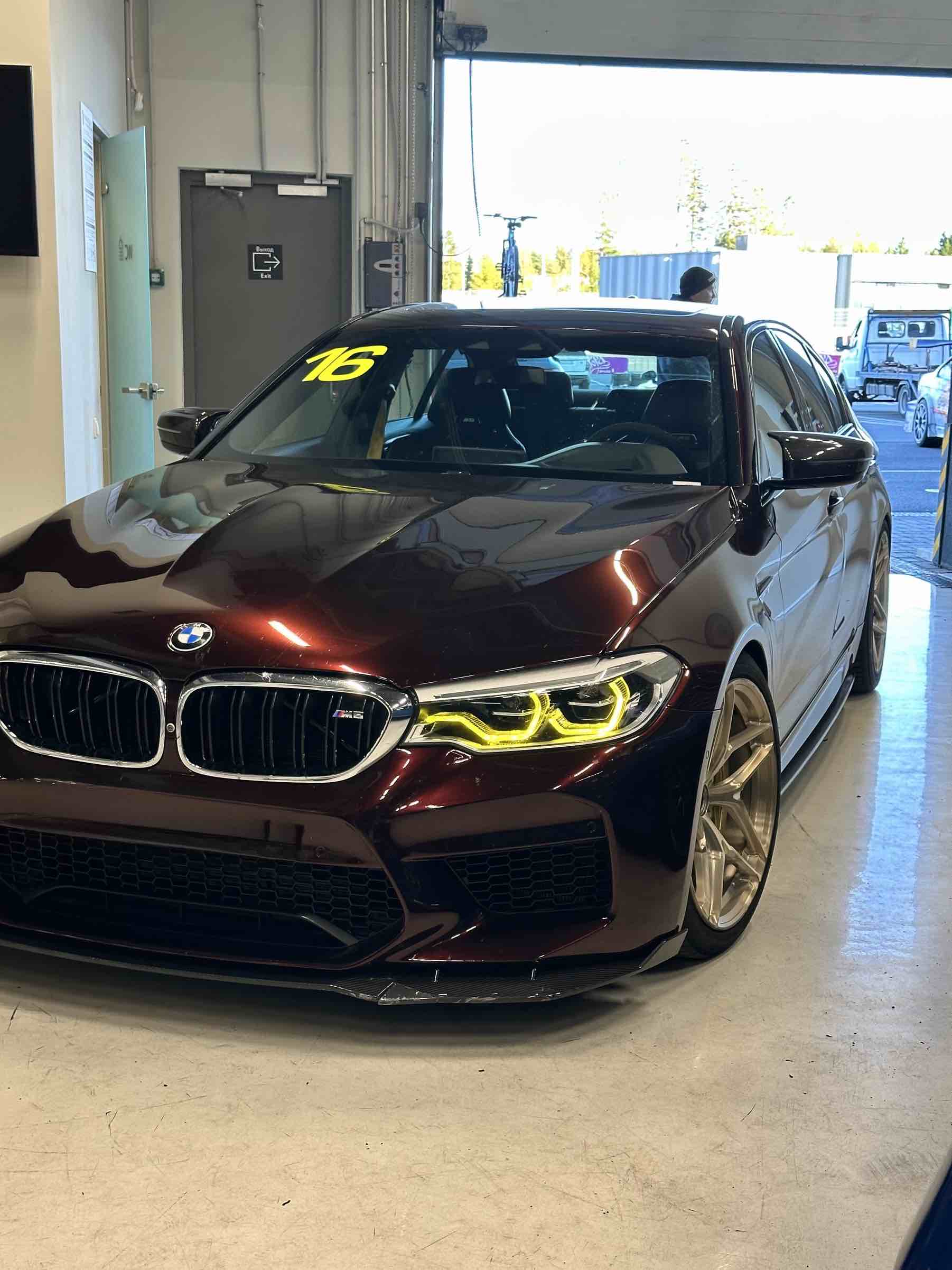 Ein burgunderroter BMW M5 Competition F90 in der Box vor der Ausfahrt auf die Rennstrecke