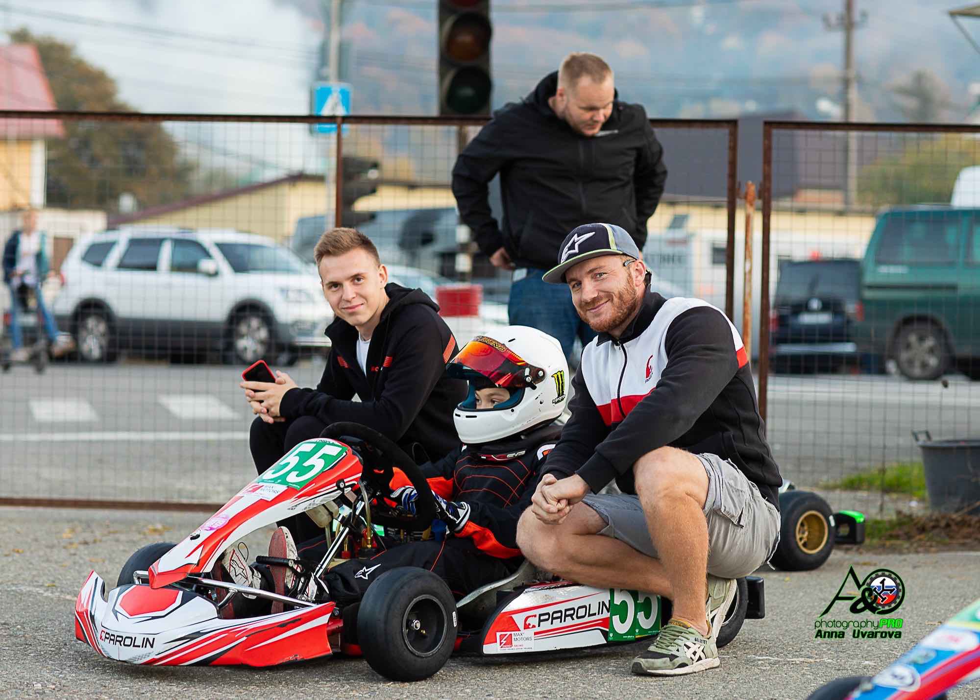 Kart-Training eines jungen Fahrers mit einem Partner unter meiner Anleitung; wir sitzen gemeinsam mit dem Fahrer auf der Rennstrecke